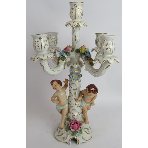 283 - A pair of hand decorated Dresden porcelain four branch candelabra with Putti decoration and a simila... 