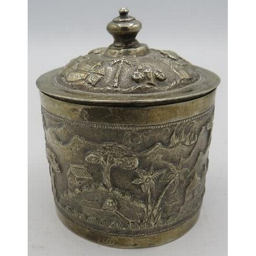 306 - A white metal round lidded Indian box. Embossed with trees, houses and temples. 4.6 troy oz/142 gram... 