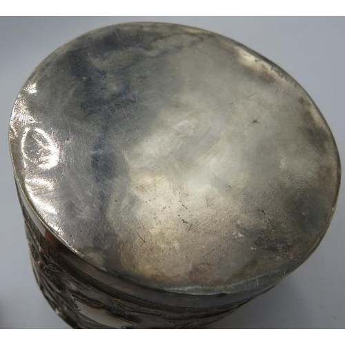 306 - A white metal round lidded Indian box. Embossed with trees, houses and temples. 4.6 troy oz/142 gram... 