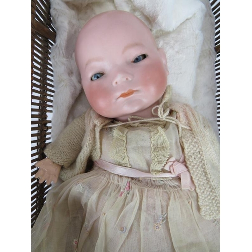 64 - A 1920's BYE-LO baby doll in period outfit with Moses basket. Head marke +IV. Height: 38cm.
Conditio... 