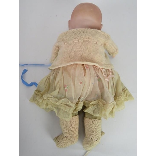 64 - A 1920's BYE-LO baby doll in period outfit with Moses basket. Head marke +IV. Height: 38cm.
Conditio... 