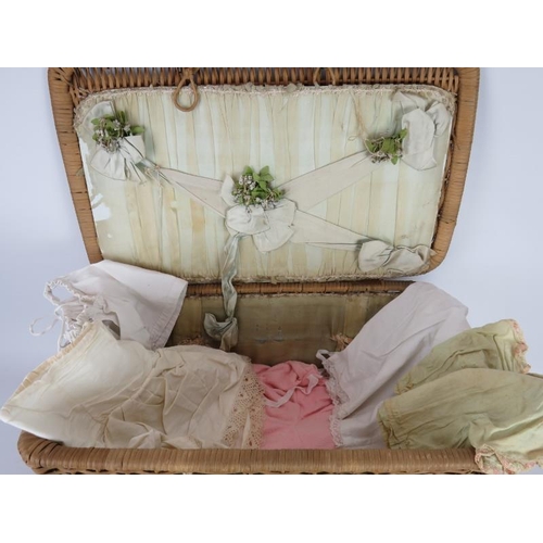 69 - A early 20th century silk lined basket with lift out tray containing 9 period dolls dresses and 6 it... 