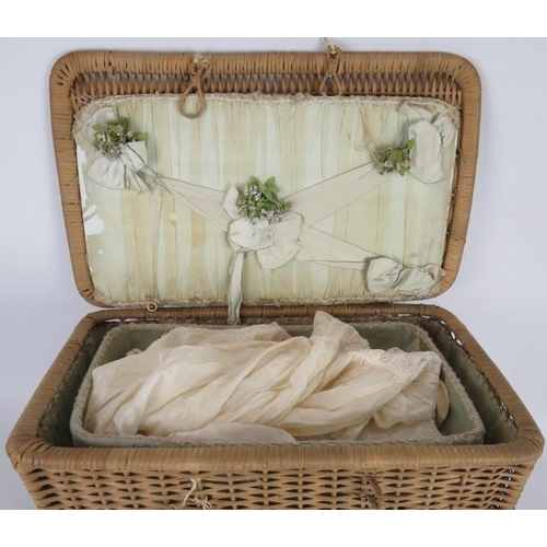 69 - A early 20th century silk lined basket with lift out tray containing 9 period dolls dresses and 6 it... 