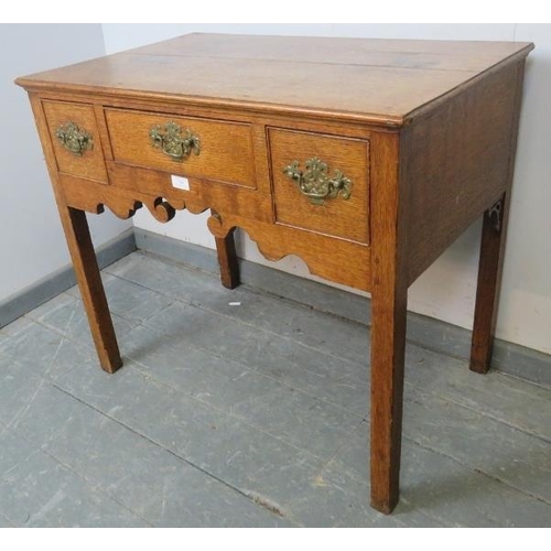 708 - An 18th century medium oak lowboy, housing three cock-beaded drawers with brass swan-neck handles an... 