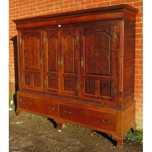 718 - A large 18th century Welsh oak livery cupboard, the inlaid cornice featuring a central butterfly, ab... 