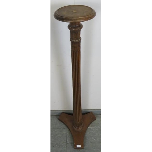 733 - An Edwardian mahogany torchere, with carved and fluted column, on a triform base with bun feet. 
Con... 