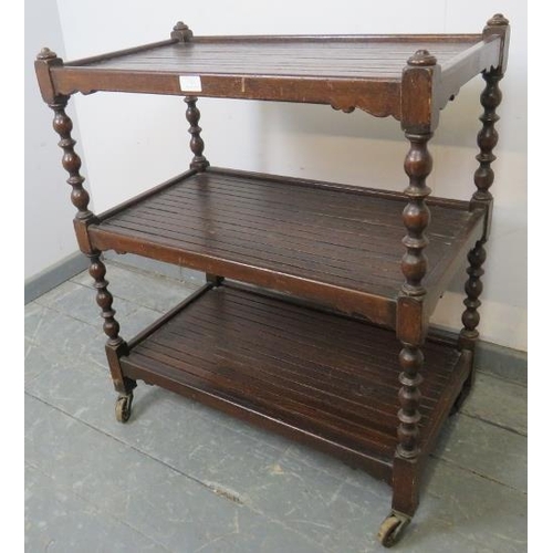 787 - An early 20th century three-tier oak drinks trolley, with baluster uprights and slatted shelves, on ... 