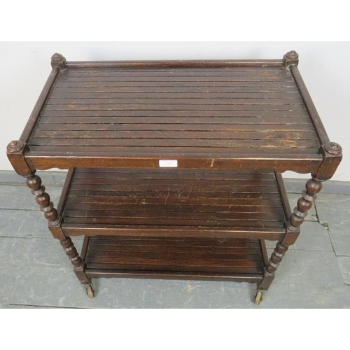 787 - An early 20th century three-tier oak drinks trolley, with baluster uprights and slatted shelves, on ... 