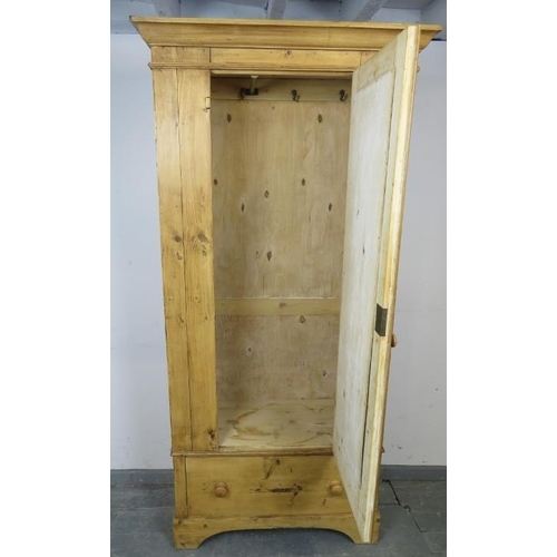 797 - An antique stripped pine single wardrobe, with hanging rail and hooks, the door with inset oval mirr... 