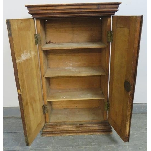 851 - An antique oak and elm wall hanging cabinet with stepped cornice, housing three fitted shelves, on a... 