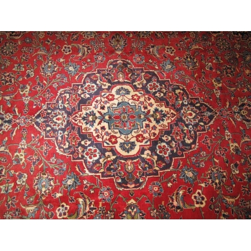 905 - A central Persian Kashan carpet central motif. Heavy foliage on claret ground and wide blue borders ... 