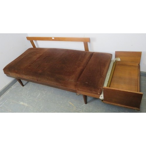 884 - A vintage mid-century teak daybed, upholstered in brown draylon, with folding side-table, on taperin... 