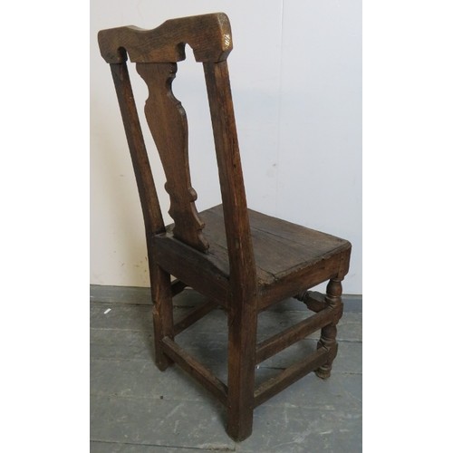 886 - An early 18th century oak hall chair, with shaped back splat, on turned and block supports with turn... 