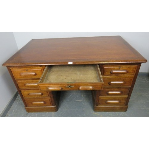 888 - An Art Deco medium oak kneehole desk, with fielded panels, housing an array of eight drawers and two... 