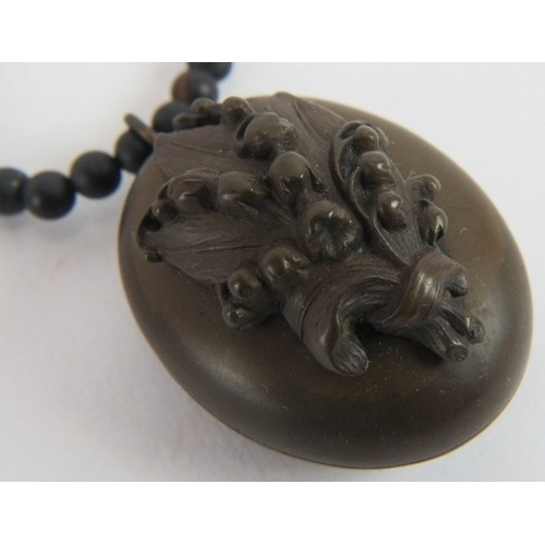 493 - A bog oak pendant/locket with carved lily of the valley and on a bog oak necklace interspersed with ... 