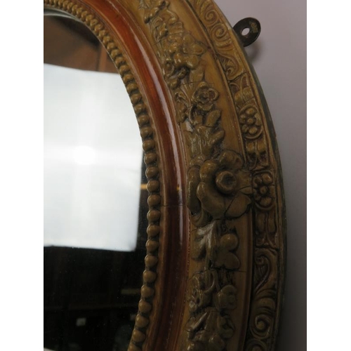 163 - A vintage relief moulded oval wall mirror, with foliate and beaded decoration, c.1900/1920, 76cm wid... 