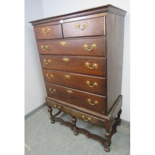 701 - An 18th century oak chest on stand, housing two short over three long drawers with brass batwing esc... 