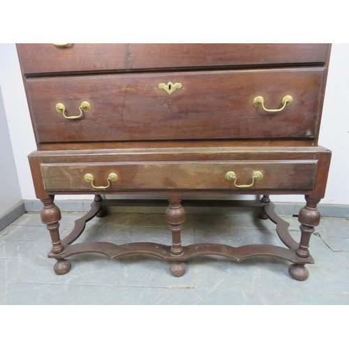 701 - An 18th century oak chest on stand, housing two short over three long drawers with brass batwing esc... 