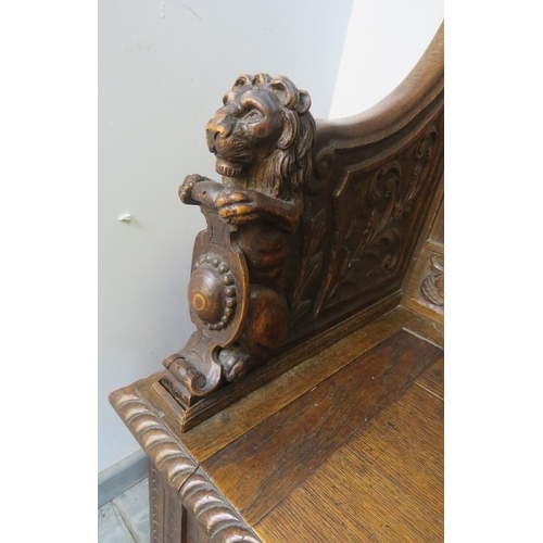 708 - A 19th century high-back oak box settle, the very ornate relief carving depicting a central lion mas... 