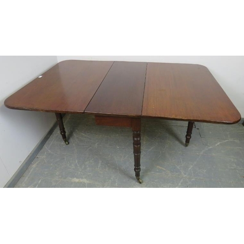 709 - An early Victorian mahogany drop-leaf dining table, on tapering turned supports with brass caps and ... 