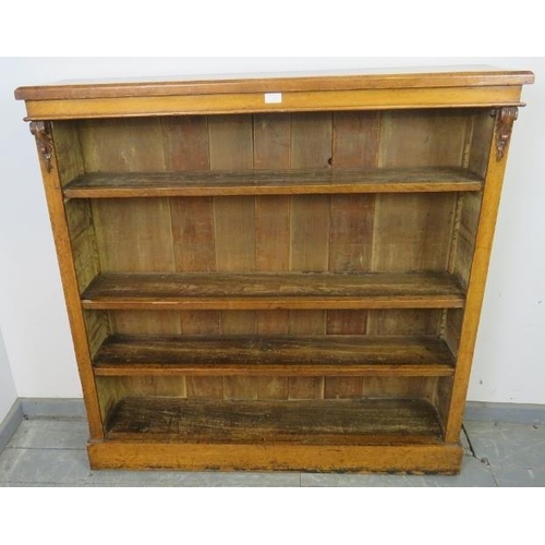 710 - A Victorian golden oak low open bookcase, of three height adjustable shelves flanked by carved corbe... 