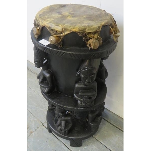 740 - A vintage ebonised African tribal drum, carved with seated figures, on square supports. 
H71cm Diame... 