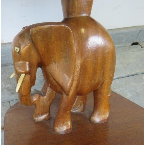 742 - A vintage teak square table with carved stand in the form of an elephant, on a plinth base with bloc... 