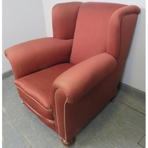 763 - An Edwardian wingback club armchair, re-upholstered in light burgundy material with silver braided r... 