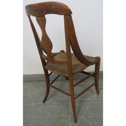 767 - A 19th century walnut child’s chair with curved sides and rush seat, on splayed supports with stretc... 