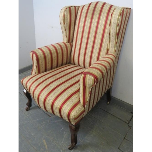 774 - An Edwardian wingback armchair, reupholstered in striped material with brass studs, on mahogany cabr... 