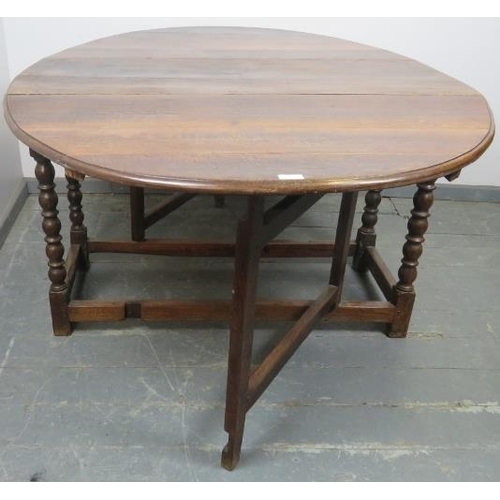 777 - An 18th century oak oval drop-leaf dining table, with gate-leg action, on turned supports with stret... 