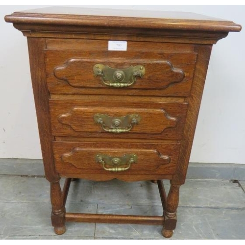 793 - A small vintage oak bedside chest, housing three long drawers with brass handles, on turned supports... 