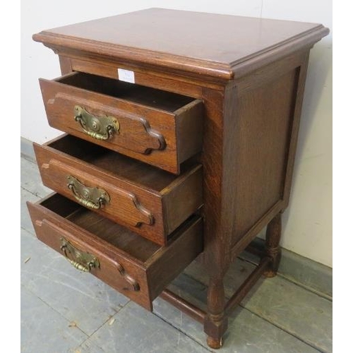 793 - A small vintage oak bedside chest, housing three long drawers with brass handles, on turned supports... 