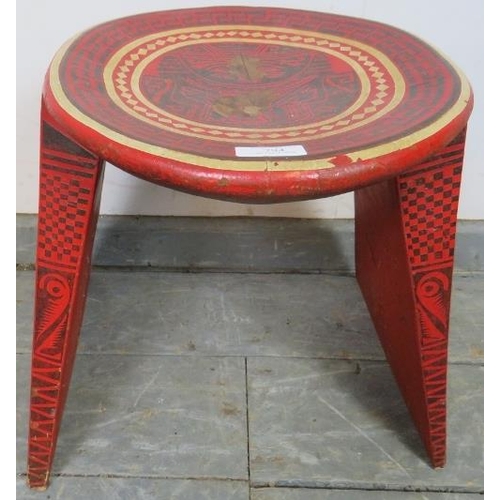 794 - A vintage Colombian wooden stool, with dished top, on triangular supports, hand-painted in red, blac... 