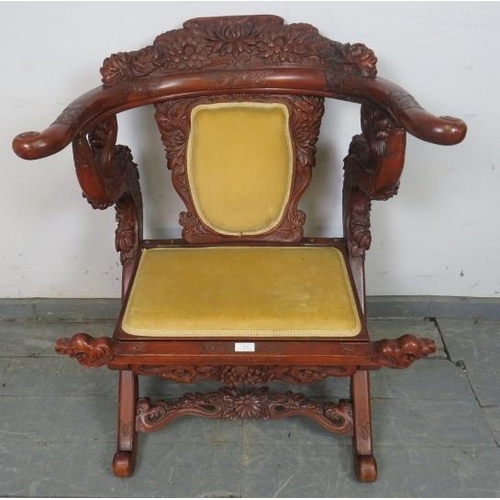 830 - An early 20th century Chinese tropical hardwood folding horseshoe chair, with very ornate carving de... 