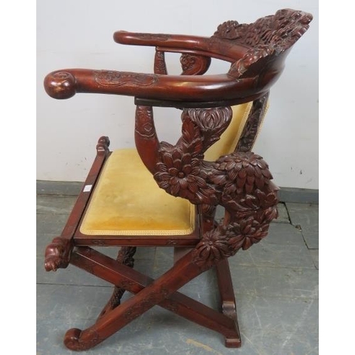 830 - An early 20th century Chinese tropical hardwood folding horseshoe chair, with very ornate carving de... 