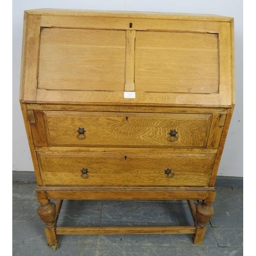 833 - A 1920s light oak bureau, the fall-front opening onto a fitted interior, above two graduated long dr... 