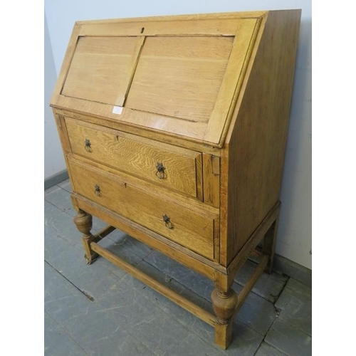 833 - A 1920s light oak bureau, the fall-front opening onto a fitted interior, above two graduated long dr... 