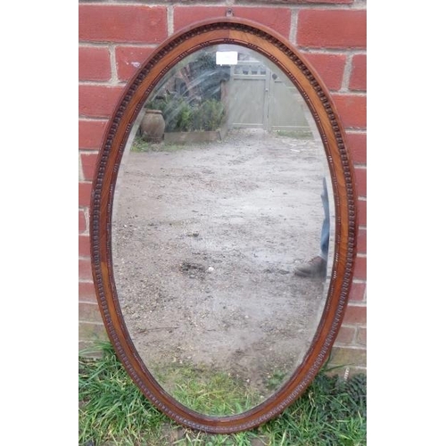 867 - A large Victorian oval bevelled wall mirror in a carved walnut surround.
H103cm W58cm (approx).
Cond... 