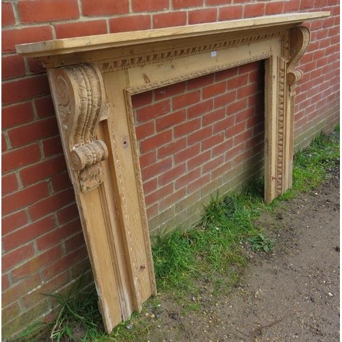 873 - A large antique stripped pine fire surround, featuring egg and dart carved border and ornate corbels... 