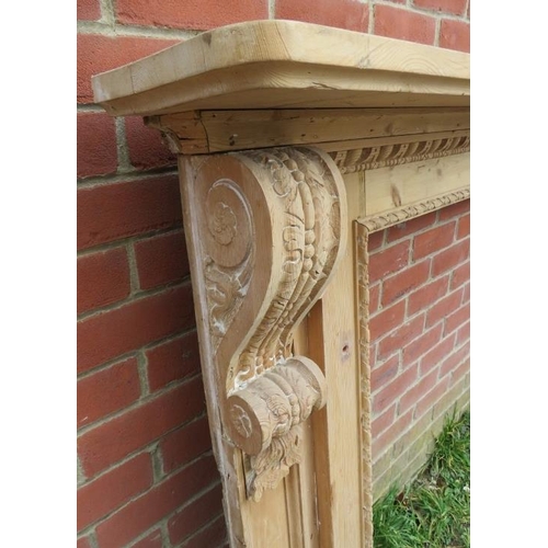 873 - A large antique stripped pine fire surround, featuring egg and dart carved border and ornate corbels... 