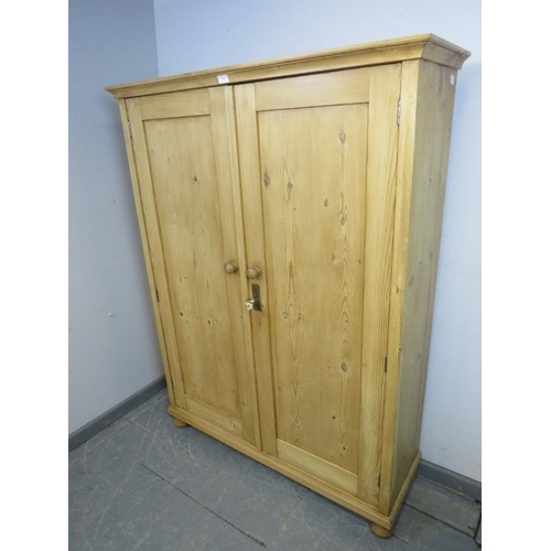 887 - An antique stripped pine pantry cupboard, the panelled doors opening onto two fitted shelves, on bun... 