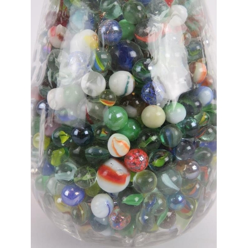 51 - A large quantity of glass marbles of mixed size and colours, collected in a glass vase. Vase: 9.1 in... 