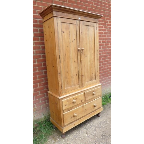 711 - An antique pine linen press/wardrobe, the top section with an array of metal hooks, the base with tw... 