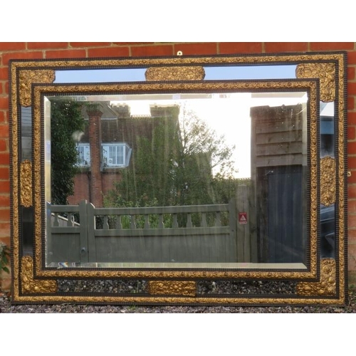 712 - A large 19th century Napoleon III ebonised cushion mirror, the sectioned bevelled glass featuring or... 