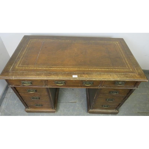 729 - An Edwardian oak pedestal desk, with inset brown leather writing surface, housing a configuration of... 