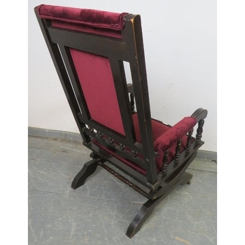 730 - An Edwardian ebonised American style ‘Dexter’ rocking chair, upholstered in plum velvet material, on... 