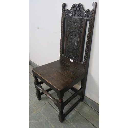 754 - An 18th century oak hall chair, the relief carved back depicting a mythical bird, on turned and bloc... 