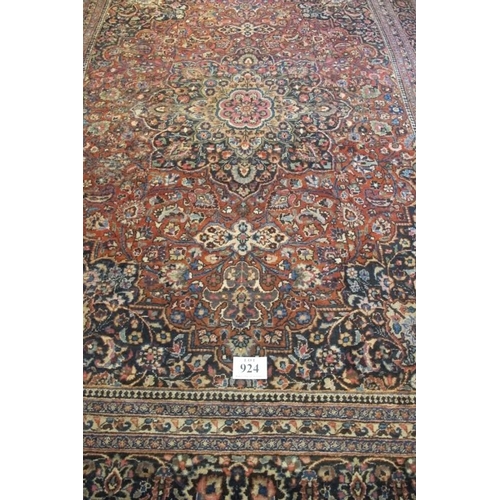 924 - A large Persian carpet c 1920's, central motif on pale red ground, with very wide blue/red/cream bor... 