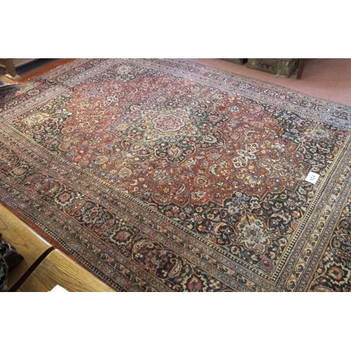 924 - A large Persian carpet c 1920's, central motif on pale red ground, with very wide blue/red/cream bor... 